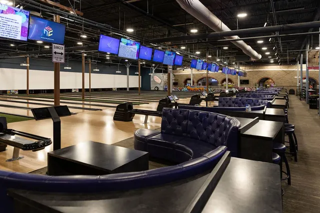 Bowling lanes and lounge booths under screens at The Alley