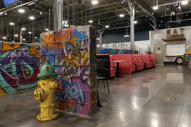 Graffiti wall, a yellow fire hydrant and red booths in The Alley