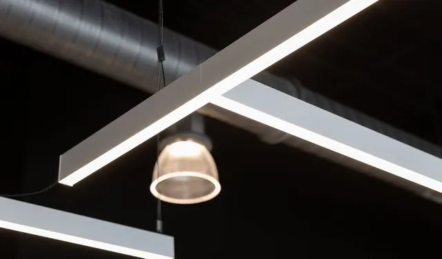 Linear light fixtures hung under a black ceiling