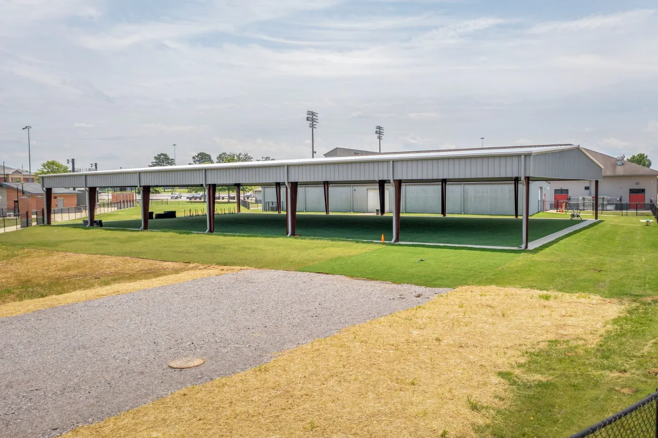 Open-sided metal training facility over green turf