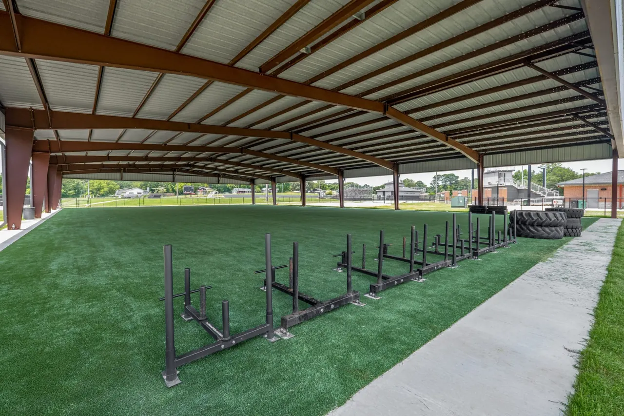 Turf and training sleds under the red steel frames of the facility